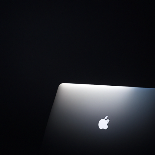 A glossy black laptop with a shiny apple logo under a spotlight